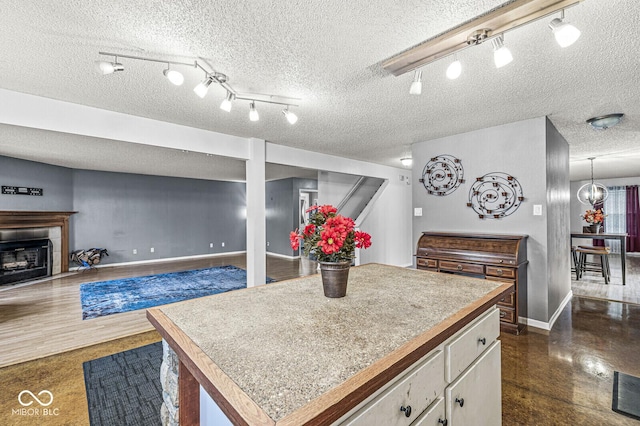 6259 Teacup Dr, Indianapolis, IN 46235 - kitchen featuring rail lighting, a kitchen island, a fireplace, white cabinetry, and a textured ceiling
