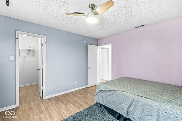 6259 Teacup Dr, Indianapolis, IN 46235 - bedroom featuring wood finished floors, a textured ceiling, a spacious closet, ceiling fan, and a closet