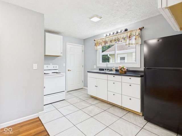 4025 Main St, Anderson, IN 46013 - kitchen with freestanding refrigerator, electric stove, white cabinetry, a textured ceiling, and dark countertops
