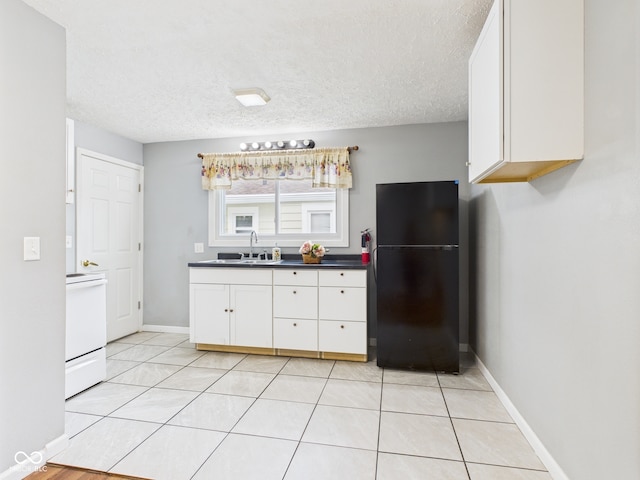 4025 Main St, Anderson, IN 46013 - kitchen featuring freestanding refrigerator, stove, white cabinets, a textured ceiling, and light tile patterned floors