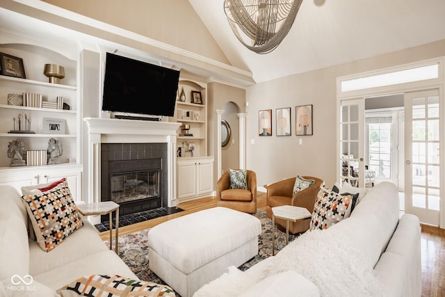 12505 Branford St, Carmel, IN 46032 - living area featuring wood finished floors, a tile fireplace, built in shelves, a chandelier, and high vaulted ceiling