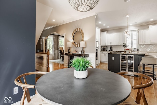 12505 Branford St, Carmel, IN 46032 - dining area featuring wine cooler, light wood finished floors, crown molding, and recessed lighting