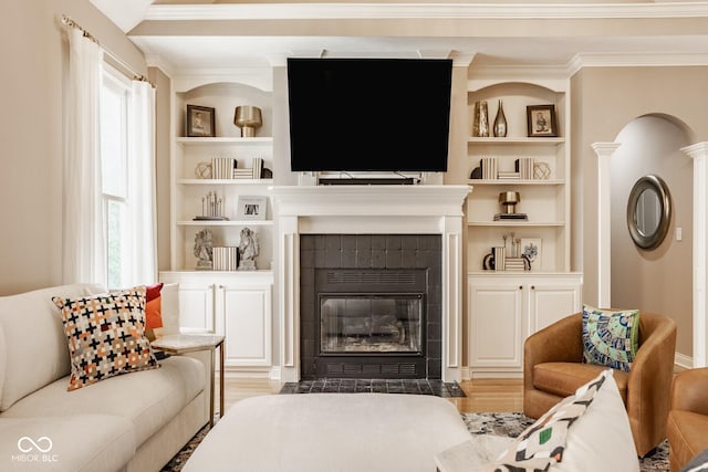 12505 Branford St, Carmel, IN 46032 - living room featuring a tiled fireplace, built in features, healthy amount of natural light, ornamental molding, and light wood-type flooring
