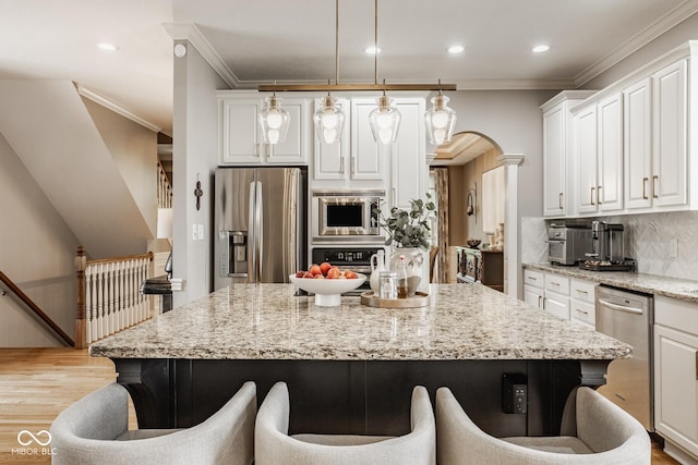 12505 Branford St, Carmel, IN 46032 - kitchen featuring appliances with stainless steel finishes, a kitchen breakfast bar, light wood finished floors, white cabinets, and a center island