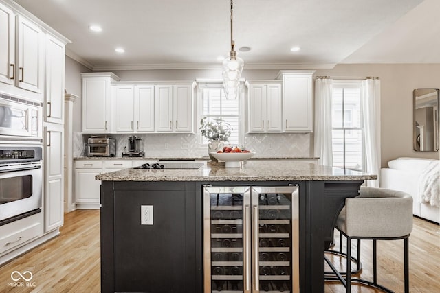 12505 Branford St, Carmel, IN 46032 - kitchen with beverage cooler, appliances with stainless steel finishes, crown molding, white cabinetry, and a breakfast bar area