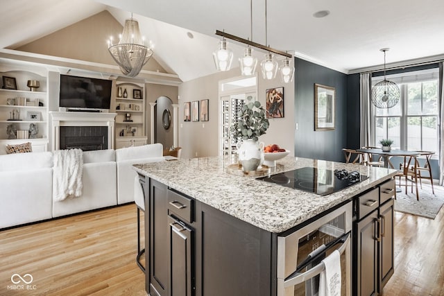 12505 Branford St, Carmel, IN 46032 - kitchen with black electric cooktop, a chandelier, light wood-style floors, vaulted ceiling, and decorative light fixtures