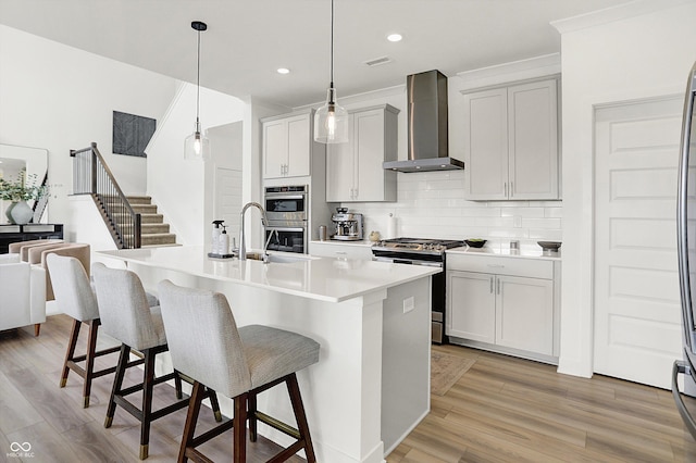 4250 Blackford Rd, Bargersville, IN 46106 - kitchen featuring stainless steel appliances, wall chimney range hood, a breakfast bar area, decorative backsplash, and light wood finished floors