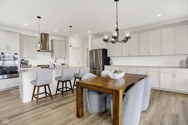 4250 Blackford Rd, Bargersville, IN 46106 - kitchen with wall chimney range hood, decorative backsplash, a chandelier, stainless steel appliances, and light wood finished floors