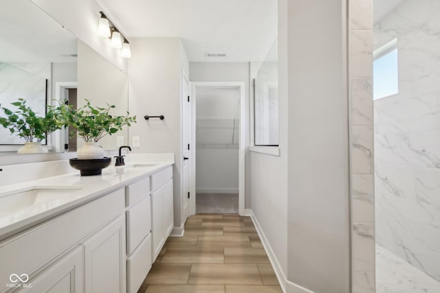 6842 Jacone Dr, Brownsburg, IN 46112 - bathroom with double vanity, a walk in closet, and wood finished floors