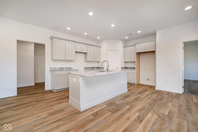 202 Asbury Dr, Anderson, IN 46013 - kitchen with light wood-style flooring, light stone counters, an island with sink, and recessed lighting