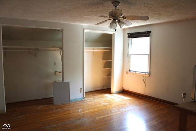 515 Hawthorne Ave, Anderson, IN 46011 - unfurnished bedroom with multiple closets, a textured ceiling, wood finished floors, and a ceiling fan
