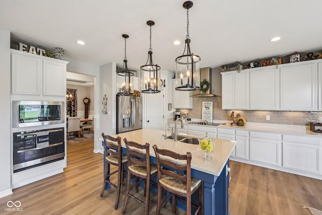 19281 Scofield Ridge Blvd, Westfield, IN 46074 - kitchen featuring appliances with stainless steel finishes, light wood finished floors, backsplash, wall chimney range hood, and recessed lighting