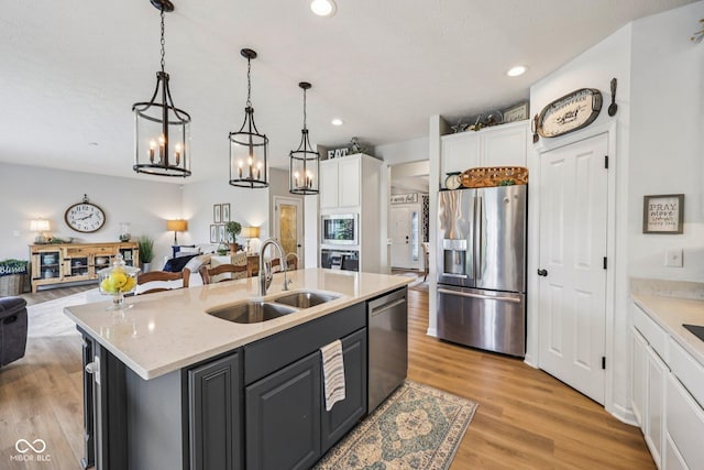 19281 Scofield Ridge Blvd, Westfield, IN 46074 - kitchen with appliances with stainless steel finishes, open floor plan, white cabinets, light wood-style floors, and a center island with sink