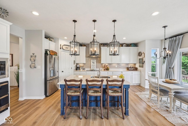 19281 Scofield Ridge Blvd, Westfield, IN 46074 - kitchen featuring appliances with stainless steel finishes, a chandelier, light countertops, decorative backsplash, and light wood-type flooring