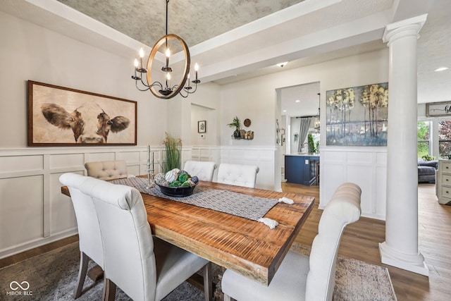19281 Scofield Ridge Blvd, Westfield, IN 46074 - dining room featuring ornate columns, wood finished floors, a decorative wall, a chandelier, and wainscoting