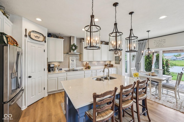 19281 Scofield Ridge Blvd, Westfield, IN 46074 - kitchen with stainless steel fridge with ice dispenser, a chandelier, wall chimney range hood, black electric stovetop, and recessed lighting