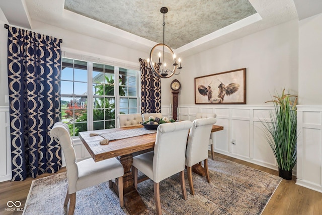 19281 Scofield Ridge Blvd, Westfield, IN 46074 - dining space with a raised ceiling, a chandelier, a decorative wall, wood finished floors, and wainscoting
