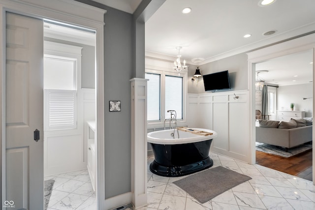 4443 Mallard Pt, Columbus, IN 47201 - bathroom featuring marble look tiles, a decorative wall, a soaking tub, wainscoting, and a chandelier