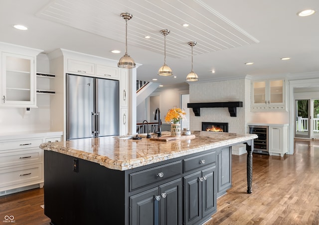 4443 Mallard Pt, Columbus, IN 47201 - kitchen featuring high quality fridge, wine cooler, white cabinets, a large fireplace, and glass insert cabinets