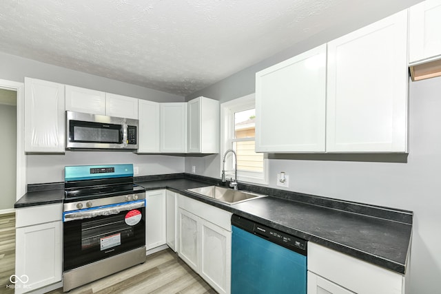 2413 Fowler St, Anderson, IN 46012 - kitchen with stainless steel appliances, light wood-style floors, white cabinets, dark countertops, and a textured ceiling