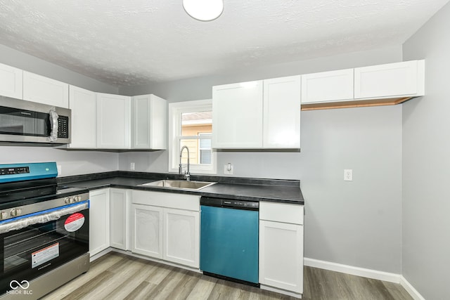 2413 Fowler St, Anderson, IN 46012 - kitchen featuring stainless steel appliances, light wood finished floors, white cabinets, dark countertops, and a textured ceiling