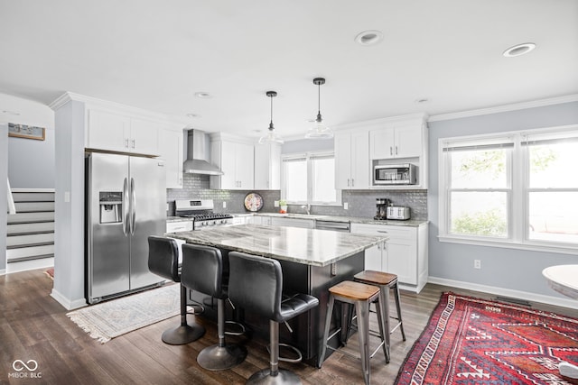 7629 Candlewood Ln, Indianapolis, IN 46250 - kitchen featuring appliances with stainless steel finishes, wall chimney range hood, white cabinetry, a center island, and crown molding