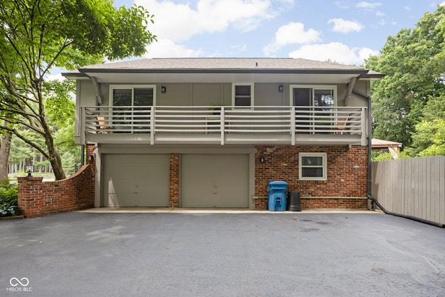 7629 Candlewood Ln, Indianapolis, IN 46250 - rear view of house featuring a balcony, brick siding, driveway, and a garage