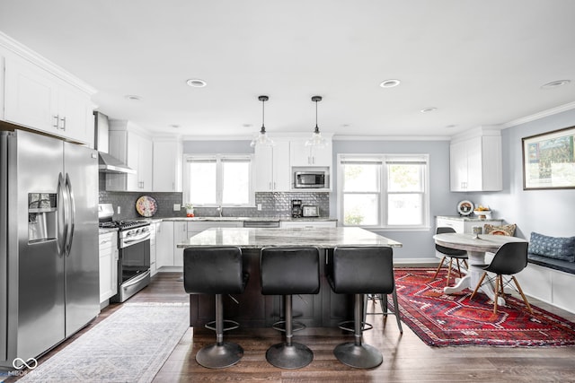 7629 Candlewood Ln, Indianapolis, IN 46250 - kitchen featuring appliances with stainless steel finishes, white cabinetry, dark wood-style floors, a kitchen island, and crown molding