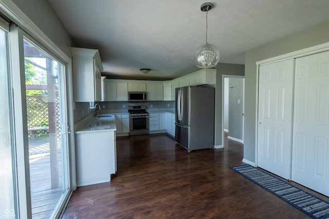 3610 Homestead Pl, Plainfield, IN 46168 - kitchen featuring appliances with stainless steel finishes, light countertops, dark wood finished floors, white cabinetry, and decorative light fixtures