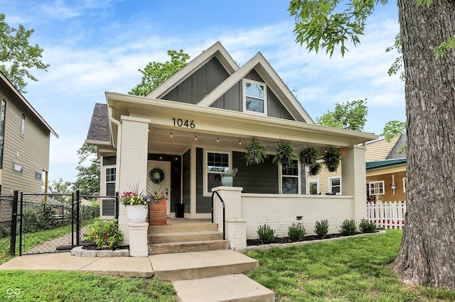 1046 N Hamilton Ave, Indianapolis, IN 46201 - craftsman-style home with board and batten siding, a gate, a porch, and brick siding
