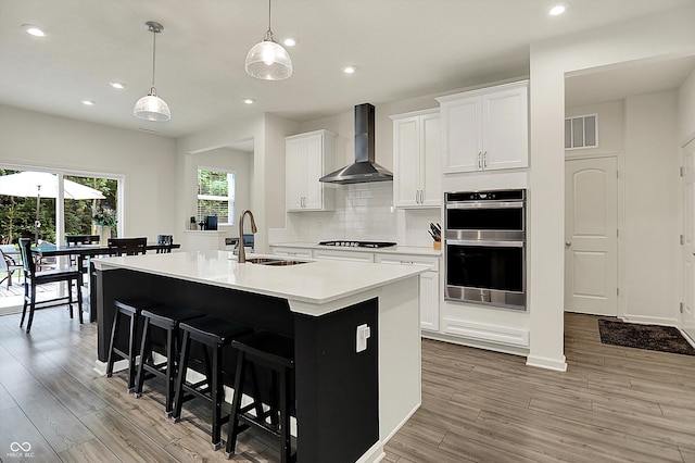 5306 Lavender Dr, Plainfield, IN 46168 - kitchen featuring wall chimney range hood, black stovetop, double oven, light wood-style flooring, and recessed lighting