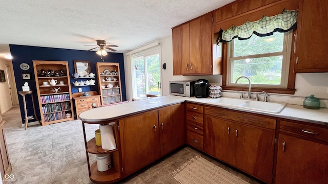202 Collier St, Columbus, IN 47201 - kitchen with light countertops, a textured ceiling, a peninsula, ceiling fan, and brown cabinetry