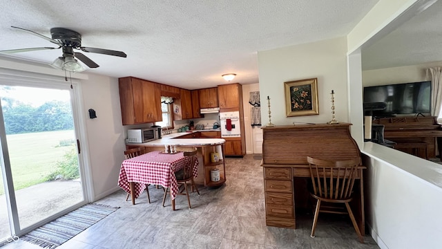 202 Collier St, Columbus, IN 47201 - kitchen featuring stainless steel microwave, brown cabinets, oven, a peninsula, and plenty of natural light