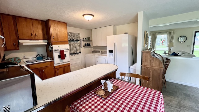 202 Collier St, Columbus, IN 47201 - kitchen featuring white appliances, under cabinet range hood, washing machine and dryer, light countertops, and brown cabinets