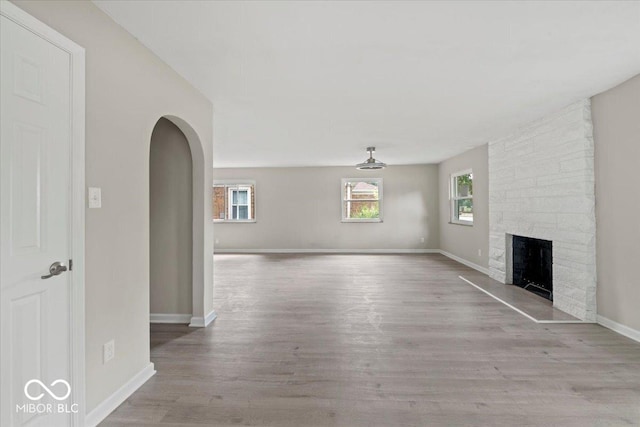 508 W 38th St, Indianapolis, IN 46208 - unfurnished living room featuring arched walkways, wood finished floors, and a fireplace