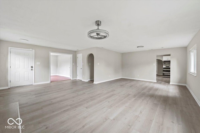 508 W 38th St, Indianapolis, IN 46208 - unfurnished living room featuring light wood finished floors, arched walkways, and ceiling fan