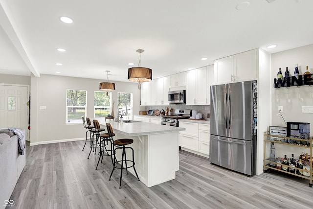 4132 Tincher Rd, Indianapolis, IN 46221 - kitchen with stainless steel appliances, a breakfast bar area, light wood-type flooring, a kitchen island with sink, and recessed lighting