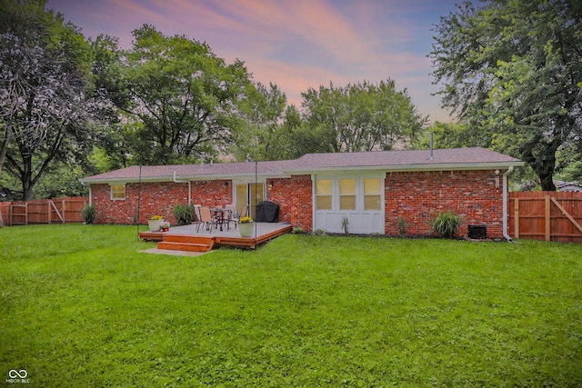 4132 Tincher Rd, Indianapolis, IN 46221 - back of property at dusk with a fenced backyard, a deck, and brick siding