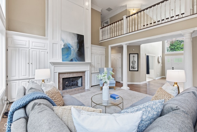 11266 Old Stone Dr, Indianapolis, IN 46236 - living room featuring ornate columns, a high ceiling, a fireplace with flush hearth, ornamental molding, and wood finished floors