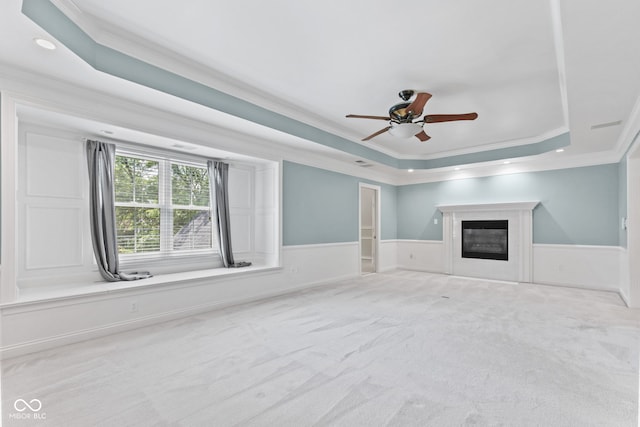 11266 Old Stone Dr, Indianapolis, IN 46236 - unfurnished living room featuring a tray ceiling, ornamental molding, a ceiling fan, a wainscoted wall, and a glass covered fireplace