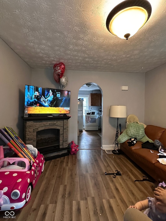 1728 N Somerset Ave, Indianapolis, IN 46222 - living area with arched walkways, wood finished floors, a textured ceiling, and a stone fireplace