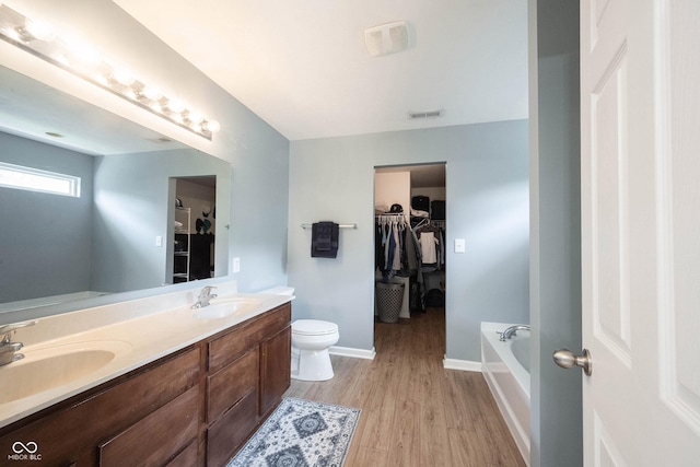 13829 Black Canyon Ct, Fishers, IN 46038 - full bathroom with double vanity, a walk in closet, a bath, and wood finished floors