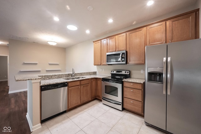 6586 Quail Run, Fishers, IN 46038 - kitchen featuring appliances with stainless steel finishes, a peninsula, light stone countertops, brown cabinetry, and recessed lighting