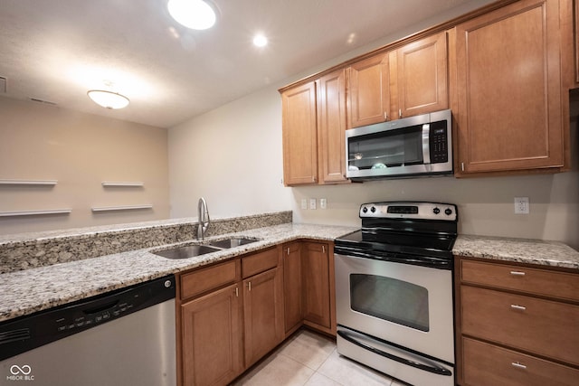 6586 Quail Run, Fishers, IN 46038 - kitchen featuring appliances with stainless steel finishes, light stone countertops, light tile patterned floors, and brown cabinetry