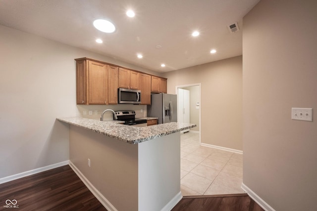 6586 Quail Run, Fishers, IN 46038 - kitchen with stainless steel appliances, a peninsula, recessed lighting, light stone counters, and brown cabinetry