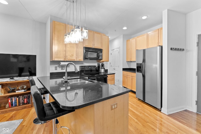 932 N Broadway St Unit 4, Indianapolis, IN 46202 - kitchen featuring black appliances, light brown cabinets, a peninsula, light wood finished floors, and a breakfast bar area
