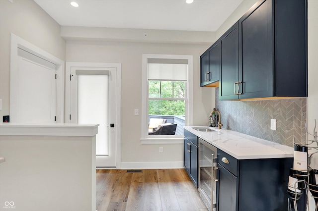 906 Berkhamsted Ln, Carmel, IN 46032 - kitchen with beverage cooler, light wood finished floors, backsplash, recessed lighting, and light stone countertops