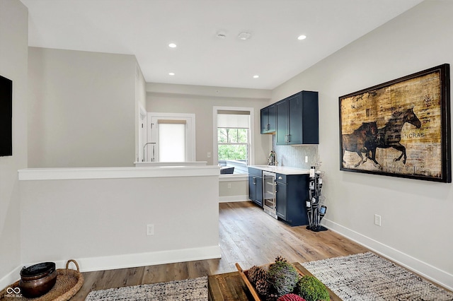 906 Berkhamsted Ln, Carmel, IN 46032 - kitchen with beverage cooler, light countertops, light wood-style flooring, recessed lighting, and blue cabinets