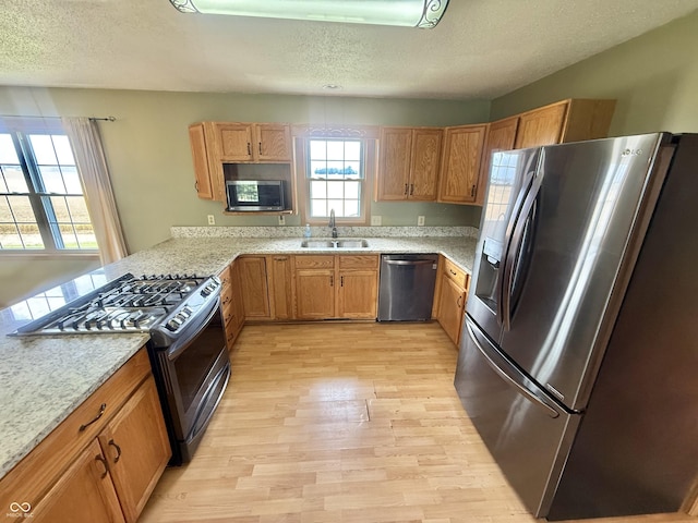 1687 Killion Ave, Seymour, IN 47274 - kitchen featuring stainless steel appliances, a textured ceiling, light wood finished floors, a peninsula, and brown cabinetry