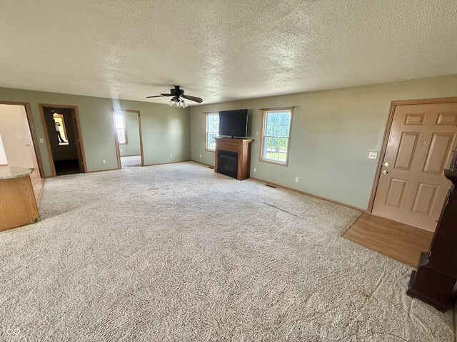 1687 Killion Ave, Seymour, IN 47274 - unfurnished living room with a ceiling fan, a textured ceiling, carpet flooring, and a fireplace